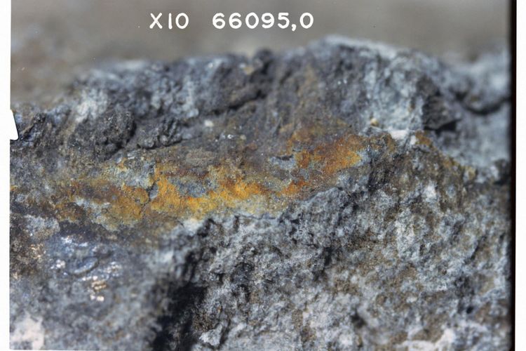 Foto close-up garam metalik atau karat di permukaan bulan 66095 Rusty Rock. Perhatikan penampilan kerak di bawah garam berwarna. Pembesaran 10 x NASA S72-48424.