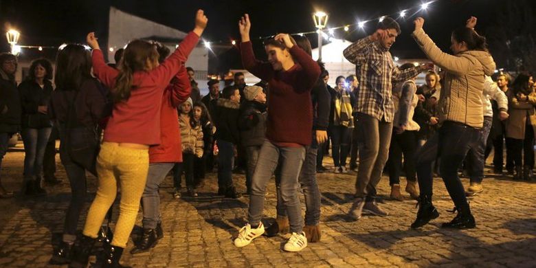 Anak-anak dan orang dewasa menari Murinheira, tarian tradisional asal Celtic, di desa Vale de Salgueiro, utara Portugal, pada epifani, Jumat (5/1/2018). (AP Photo/Armando Franca)