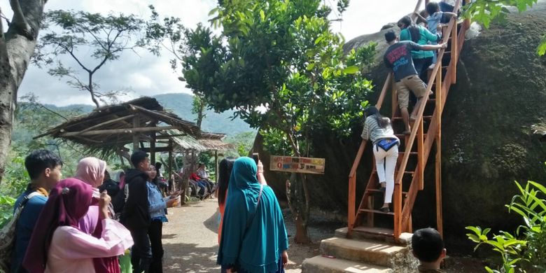 ANTRI--Warga antri naik atap rumah batu Patrick Sponge Bob milik Sutini di Dusun Mujing, Desa Genengharjo, Kecamatan Tirtomoyo, Kabupaten Wonogiri, Jawa Tengah dengan tangga kayu yang sudah dibuat permanen. 
