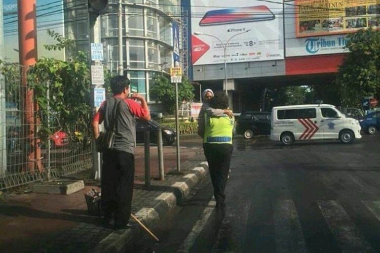 Anggota Satuan Lalulintas Polrestabes Makassar, Aiptu Chaterina Yani menggendong nenek yang kelelahan.