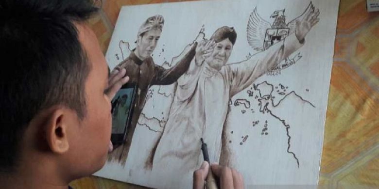 Pelukis muda Temanggung mengabadikan calon presiden Joko Widodo dan Prabowo Subianto bergandeng tangan saat deklarasi kampanye damai Pemilu 2019 dalam lukisan pyrography.