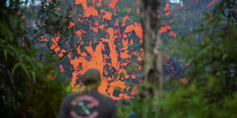 Seorang warga Hawaii melihat luapan lahar yang keluar dari celah tebing gunung Kilauea di Pulau Besar, Hawaii. Sekitar 10.000 warga telah diminta mengungsi untuk menghindari dampak letusan gunung berapi yang meletus pada Jumat (4/5/2018).