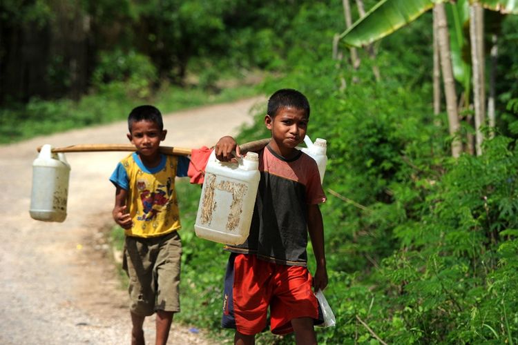 Anak-anak membawa air dengan jeriken di sebuah desa di Sumba Barat di Provinsi Nusa Tenggara Timur, Jumat (20/10/2017). Badan Penanggulangan Bencana Daerah (BPBD) Nusa Tenggara Timur menyatakan hingga saat ini sudah 14 dari 22 kabupaten/kota di wilayah itu mengalami kekeringan akibat kemarau panjang.