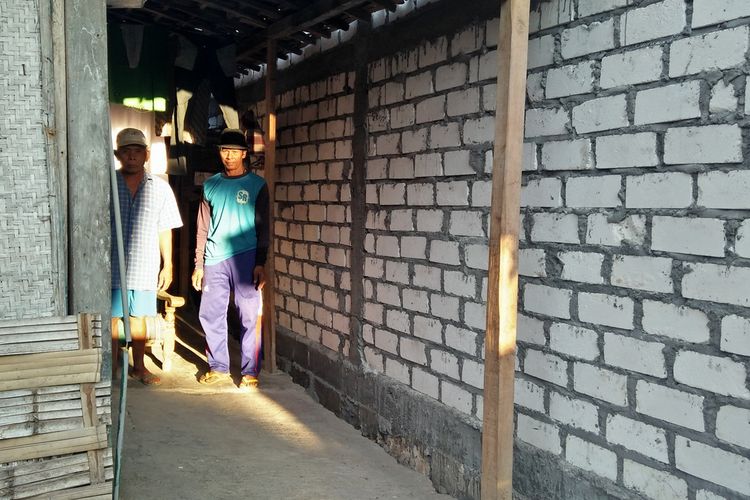 Kaslan (kiri) saat berada di depan rumah miliknya yang tertutup tembok bangunan tetangga di Desa Wudi, Kecamatan Sambeng, Lamongan, Minggu (1/9/2019).