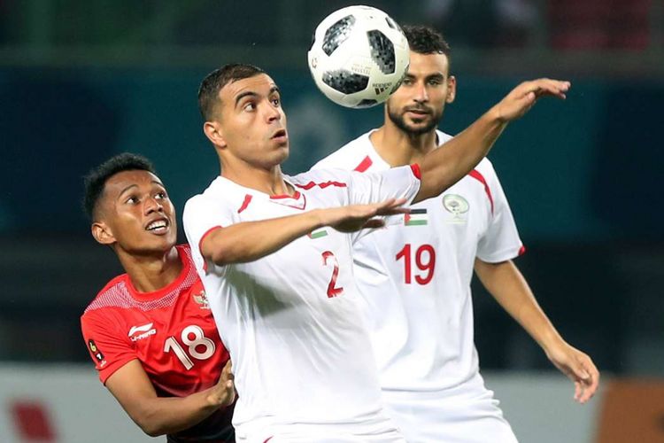 Pesepak bola Indonesia Irfan Jaya (kiri) mencoba merebut bola dari pemain Palestina Amed Qatmish (tengah) pada pada babak penyisihan sepakbola Grup A Asian Games 2018 di Stadion Patriot Bekasi, Selasa (15/08/2018).
