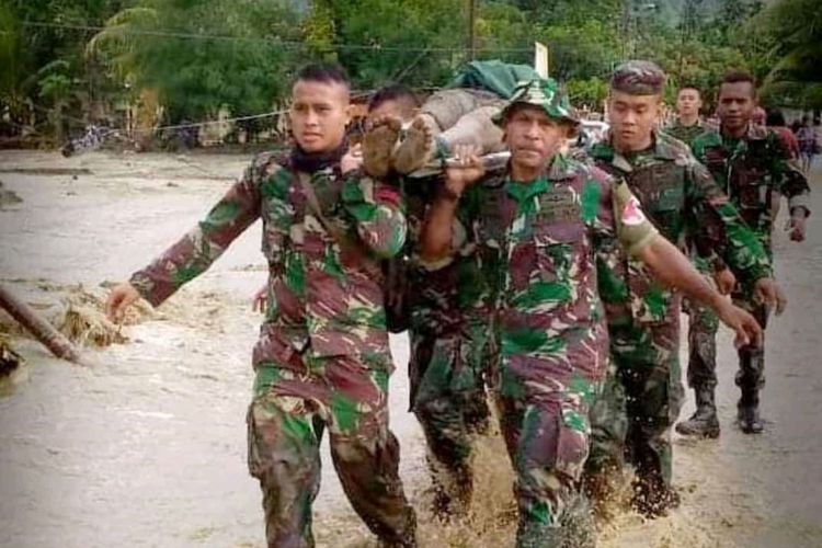 Prajurit TNI tengah mengevakuasi korban banjir bandang