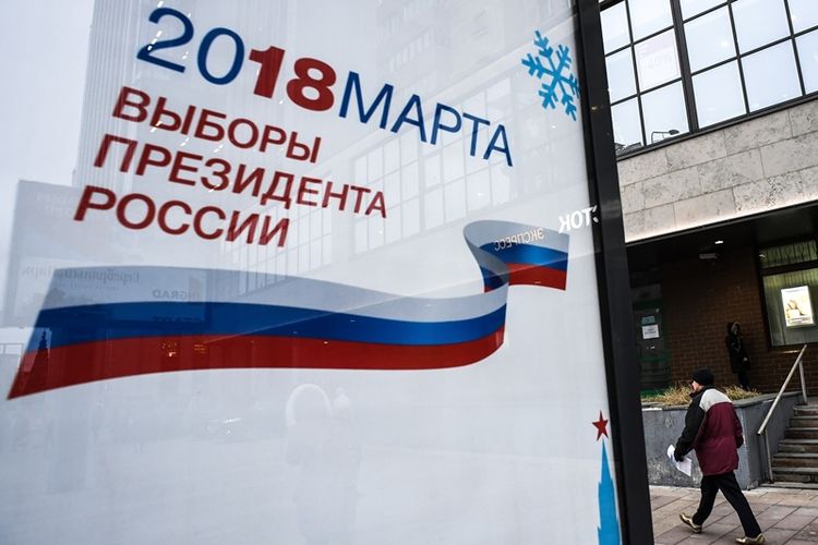 Warga Moskwa melintas di dekat poster pengumuman pemilihan presiden yang akan digelar 2018 mendatang. Masa kampanye telah resmi dimulai pada 18 Desember 2017.