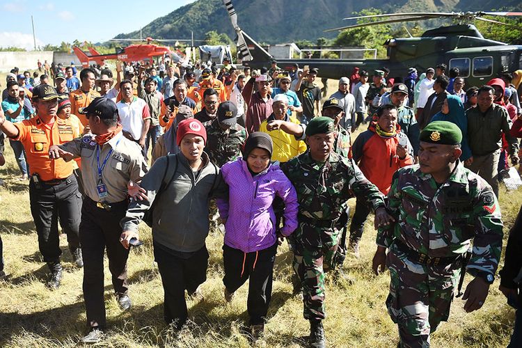 Petugas membantu pendaki Gunung Rinjani yang sempat terjebak longsor akibat gempa bumi, Suharti (tengah), setelah berhasil dievakuasi dan tiba di Lapangan Sembalun Lawang, Lombok Timur, NTB, Selasa (31/7/2018). Tiga orang pendaki yang terjebak akibat gempa berhasil dievakuasi menggunakan helikopter.