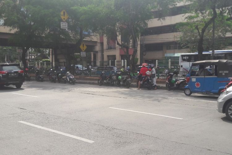 Sejumlah sepeda motor milik pengemudi ojek online diparkir di tepian jaur Transjakarta di Mangga Dua, Jakarta Utara, Minggu (15/4/2018).