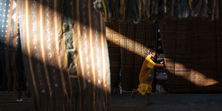 Seorang anak bermain di antara kain tenun ikat di Pasar Alok, Maumere, Sikka, Nusa Tenggara Timur (NTT), Selasa (31/7/2018). Di Pasar Alok, setiap Selasa mulai pukul 06.0013.00 Wita merupakan hari khusus bagi perajin seantero Kabupaten Sikka dan daerah lainnya untuk menjual kain tenun ikat hasil kerajinan tangan yang dibuat dengan mesin tenun tradisonal.