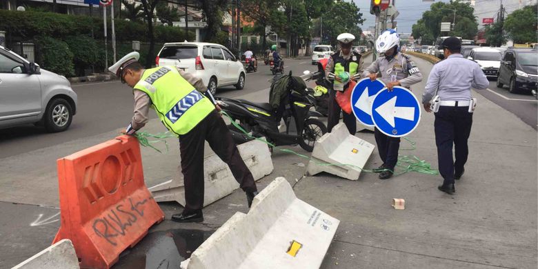 Sejumlah petugas kepolisian berusaha merapikan pembatas jalan di Simpang Duren Tiga, Pancoran, Jakarta Selatan yang dibongkar paksa puluha warga, Sabtu (19/5/2018).
