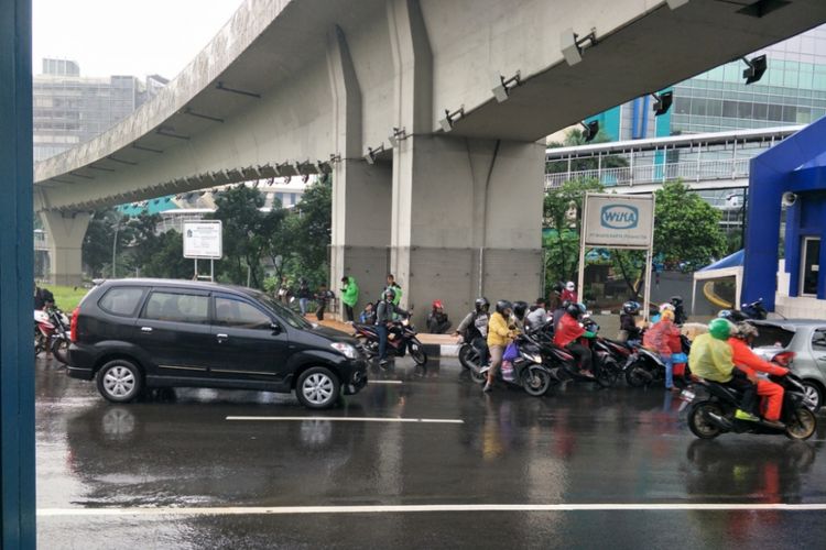Pengendara sepeda motor berteduh di kolong Simpang Susun Semanggi, Jumat (9/11/2018).