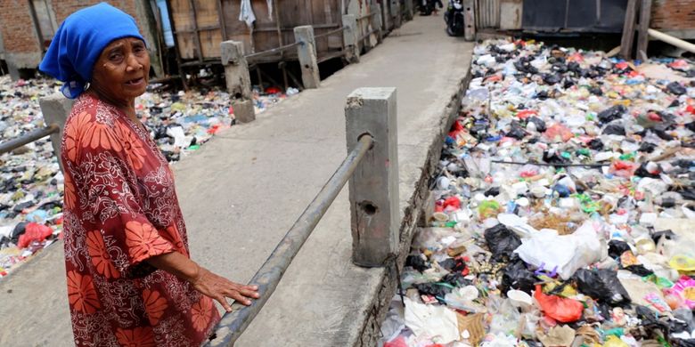 Warga melintas di Kali Gendong, Waduk Pluit, Penjaringan, Jakarta Utara, Selasa (14/3/2017). Kurangnya kesadaran masyarakat membuang sampah sembarangan mengakibatkan sampah plastik dari rumah tangga nyaris menyerupai daratan tersebut menumpuk di sepanjang Kali Gendong.