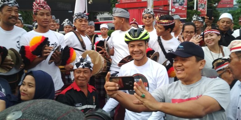 Gubernur Jawa Tengah Ganjar Pranowo terlihat memantau lokasi panggung sembari mengayuh sepeda. Sesekali dia menyapa warga dan melayani masyarakat untuk berfoto. 