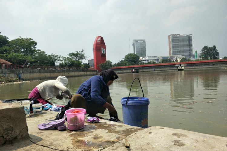 Tiga orang wanita paruh baya mencuci pakaian di tepi Sungai Cisadane, Kota Tangerang, Banten, Minggu (30/9/2018). 
