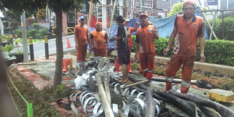 Petugas PPSU Kelurahan Kuningan Barat atau pasukan oranye saat menemukan kulit kabel dari dalam gorong-gorong Jalan Gatot, Jakarta Selatan. 