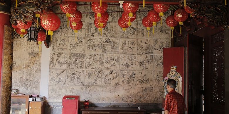 Salah satu pengunjung melihat panel-panel mural Klenteng Cu Ang Kiong yang terletak di Desa Dasun, Kecamatan Lasem, Kabupaten Rembang, Jawa Tengah, Minggu (12/2/2017). Mural monokrom hitam putih itu berasal dari 100 panel ‘komik’ Fengshen Yanyi dikenal juga dengan nama Fengshenbang atau Kisah Mitologi Dewa-Dewa Taois karya Xu Zhonglin. Fengshen Yanyi ditulis pada masa Dinasti Ming (1368-1644) dan diterbitkan pada tahun 1550.