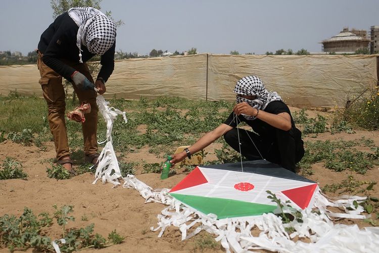 Para pemuda Palestina mempersiapkan layang-layang yang akan dipasangi bom molotov sebelum diterbangkan ke wilayah Israel.