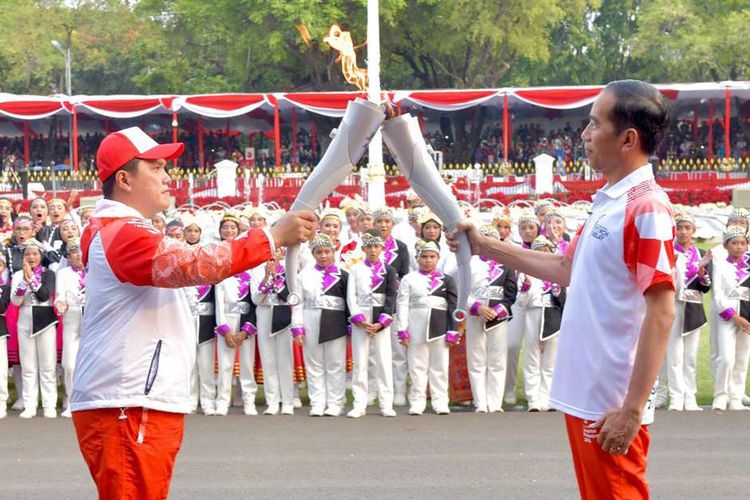 Presiden Joko Widodo (kanan) menyerahkan api obor Asian Games kepada Ketua Penyelenggara Asian Games 2018 (Inasgoc) Erick Thohir di halaman Istana Merdeka, Jakarta, Jumat (17/8/2018). Kirab obor memasuki tahap akhir dengan tiba di Jakarta, dan akan berlanjut untuk penyalaan obor Asian Games 2018 dalam acara pembukaan di Stadion Utama Gelora Bung Karno, Sabtu (18/8/2018).