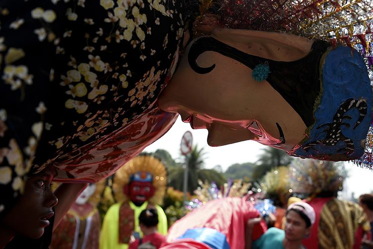 Foto dirilis Rabu (24/7/2019), memperlihatkan seorang warga mengangkat ondel-ondel ketika mengikuti pawai Lebaran Betawi di Monas, Jakarta. Lebaran Betawi yang telah berlangsung ke-12 kalinya ini untuk pertama kalinya digelar di Monas pada tahun ini, menampilkan berbagai kesenian, kuliner, hingga rumah khas Betawi