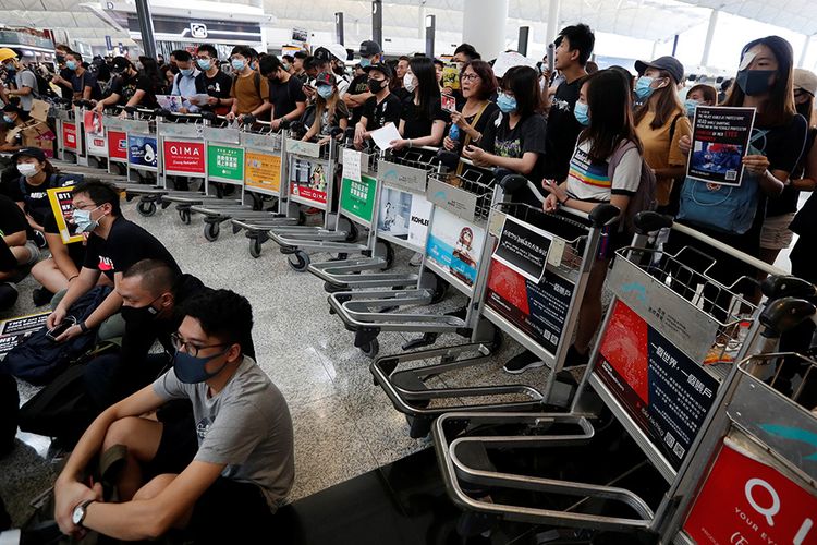 Pengunjuk rasa anti-pemerintah berdiri di sebuah barikade yang dibuat dari troli bandara saat berunjuk rasa di Bandara Hong Kong, China, Selasa (13/8/2019). Demo Hong Kong berlangsung intens dalam dua bulan terakhir dan berujung ricuh sejak UU Ekstradisi yang kontroversial mulai mendapat penolakan dari masyarakat.