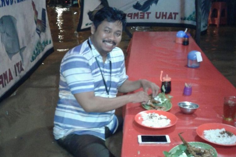 Ahmad Saiful Bahri atau Ipunk makan di tengah banjir Jatinegara, Jakarta.