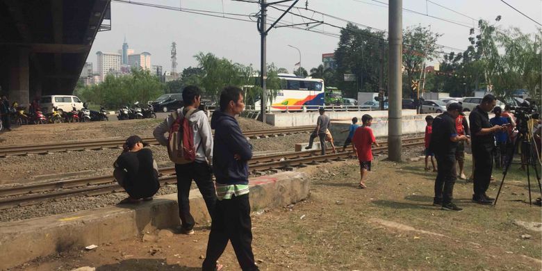 Sejumlah warga khususnya anak-anak terlihat berlarian melintasi rel kereta yang berada di sekitar Kali Grogol, Jakarta Barat. Adapun warga berlarian untuk melihat kemunculan buaya di Kali Grogol. Warga berlarian melintasi rel kereta tanpa memperdulikan tanda bahwa kereta akan melintas, Jumat (29/6/2018).