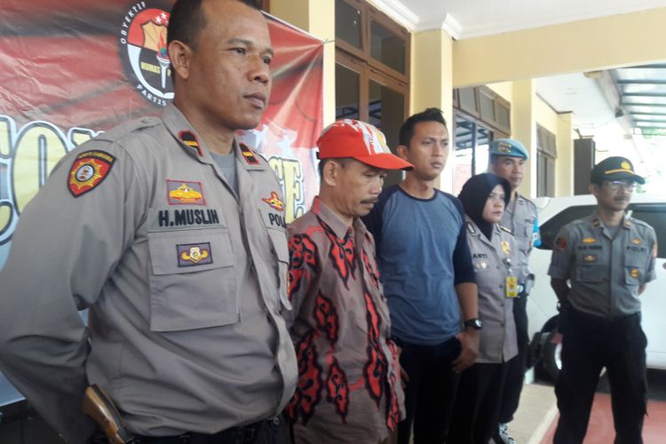 Guru PNS AS (bertopi) sebelum memberikan keterangan pers di Mapolres Garut, Selasa (21/5/2019). AS dotangkap karena menyebarkan pesan pengeboman massal di Jakarta via WhatsApp. 