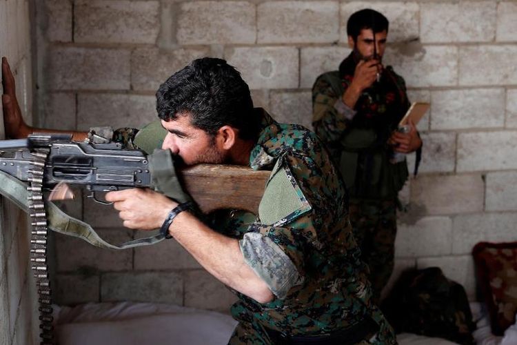Seorang anggota milisi Kurdi Suriah YPG melepaskan tembakan ke arah posisi ISIS di kota Raqqa.