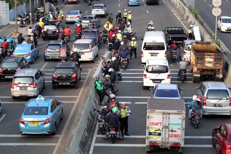 Polisi melakukan razia sepeda motor yang nekat menerobos ke jalan layang non tol (JLNT) Kampung Melayu-Tanah Abang, Jakarta, Selasa (25/7/2017). Pengendara motor masih nekat memasuki dan melintasi JLNT tersebut baik dari arah Tanah Abang maupun Kampung Melayu. KOMPAS IMAGES/KRISTIANTO PURNOMO