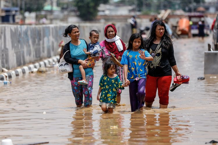 Warga berjalan melintasi banjir di Kampung Pulo, Jatinegara, Jakarta Timur, Selasa (6/2/2018). Banjir merendam ratusan rumah warga akibat luapan air dari Sungai Ciliwung.
