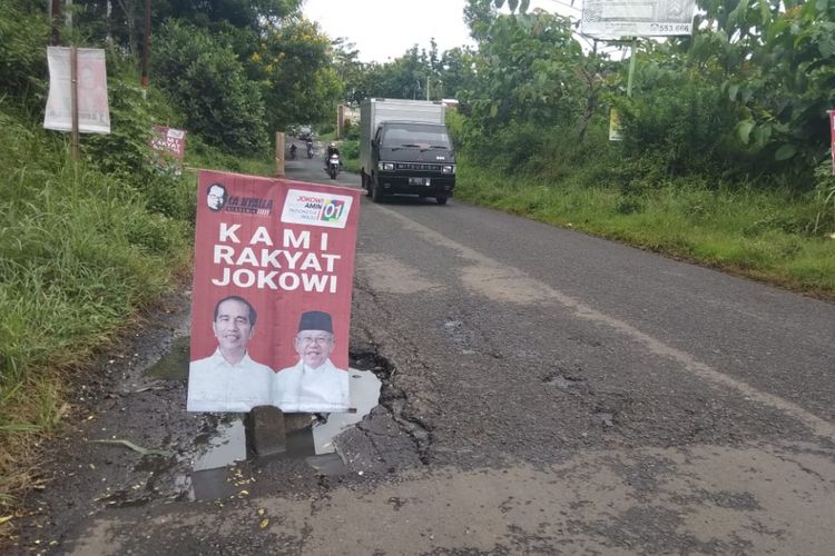 Poster pasangan calon presiden dan wakil presiden nomor urut 01 Jokowi - Maruf Amin dijadikan sebagai penanda jalan berlubang di Jalan Joyo Agung, Kota Malang, Kamis (7/3/2019)