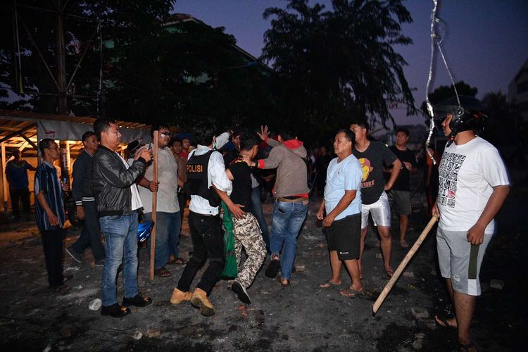 Polisi dan warga menangkap seorang yang diduga menjadi provokator pembakaran mobil di Komplek Asrama Brimob, Petamburan, Jakarta, Rabu (22/5/2019).