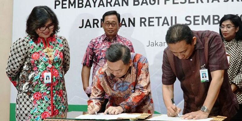 Direktur PT Bank Central Asia Tbk (BCA) Santoso (tengah) dan Direktur Keuangan & Investasi BPJS Kesehatan Kemal Imam Santoso (kanan) disaksikan oleh Direktur Perluasan & Pelayanan Peserta BPJS Kesehatan Andayani Budi Lestari (kiri) menandatangani Surat Edaran Bersama perihal Implementasi Layanan Autodebet BCA untuk Pembayaran Iuran Peserta Program Jaminan Kesehatan Nasional-Kartu Indonesia Sehat (JKN-KIS) di Jakarta, Rabu (18/04). 