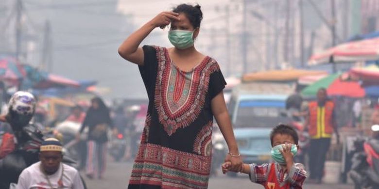 Seorang ibu dan anaknya mengenakan masker medis saat asap kebakaran hutan dan lahan (Karhutla) menyelimuti Kota Pekanbaru, Riau, Selasa (10/9/2019). 