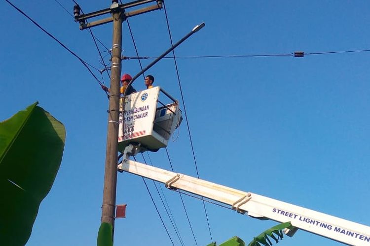 Petugas tengah memasang PJU dengan memanfaatkan tiang listrik di jalur alternatif Salajamber, Sukaluyu, Cianjur, Jawa Barat sebagai persiapan menyambut arus mudik lebaran tahun ini