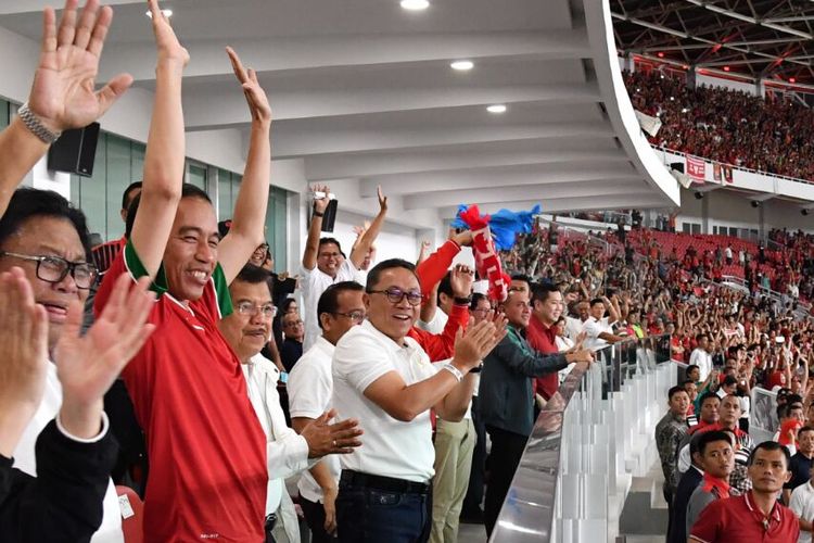 Presiden Joko Widodo berdiri dan mengangkat tangan saat tim nasional Indonesia mencetak gol ke gawang Islandia di Stadion Utama Gelora Bung Karno, Senayan, Jakarta, Minggu (14/1/2018).