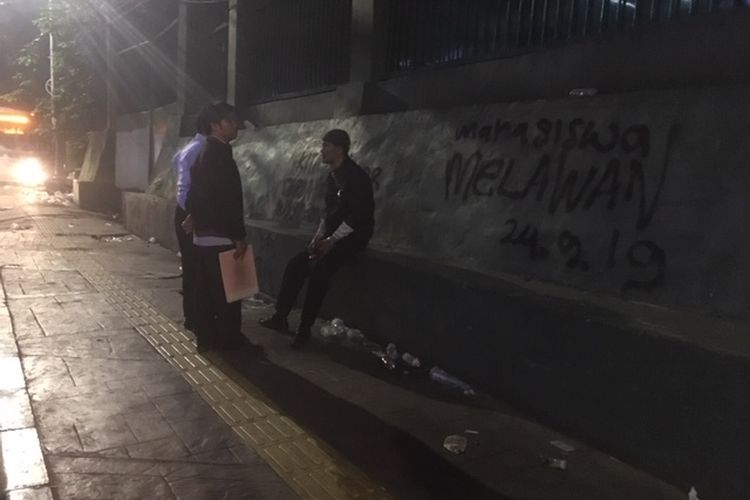 Warga bercengkerama di depan coretan mahasiswa di tembok pagar kompleks parlemen di Senayan, Jakarta. Gambar diambil pada Rabu (25/9/2019) dini hari. Lokasi coretan berada di seberang Stasiun Palmerah, Jl Tentara Pelajar, Jakarta Pusat. Coretan dibuat para mahasiswa yang menggelar demo pada Selasa (24/9/2019).