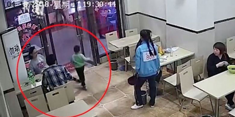 Potongan rekaman video yang memperlihatkan seorang perempuan menjulurkan kakinya ke arah bocah empat tahun yang hendak berjalan ke pintu di Baoji, China, pada pekan lalu (19/4/2018).