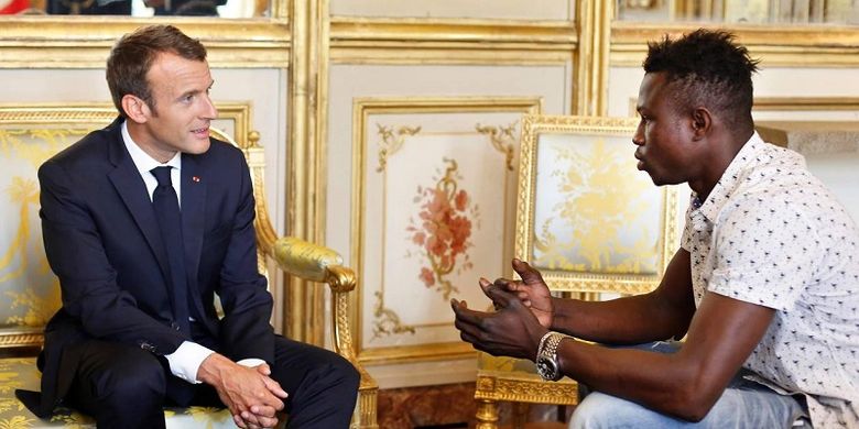 Presiden Perancis Emmanuel Macron berbincang dengan Mamoudou Gassama di Istana Elysee Senin (28/5/2018). Gassama menuai pujian setelah memanjat gedung demi menyelamatkan seorang bocah Sabtu (26/5/2018).