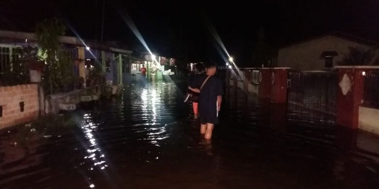Warga melintasi jalan yang dilanda banjir akibat luapan air Sungai Siak di Kecamatan Rumbai Pesisir, Pekanbaru, Riau, Kamis (22/11/2018).