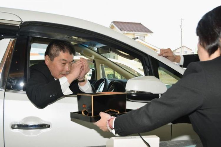 Seorang pria yang berkabung dapat memberikan uang duka cita dan dupa di jendela drive-thru di rumah duka Aishoden, Nagano, Jepang. (Japan Today)