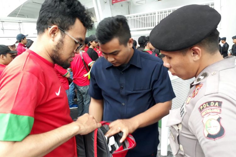 Petugas sedang memeriksa isi tas suporter timnas Indonesia pada laga versus Islandia di Stadion SUGBK, Minggu (14/1/2018).
