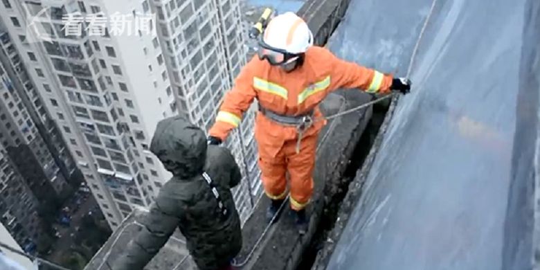 Gambar memperlihatkan petugas pemadam kebakaran di Bijie, China, berusaha membujuk bocah berusia delapan tahun yang berniat bunuh diri dari lantai 33 karena tak mau sekolah.