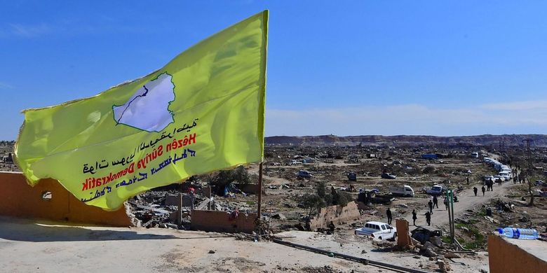 Bendera Pasukan Demokratik Suriah (SDF) dibentangkan di Baghouz, desa terpencil dekat perbatasan Irak. Bendera itu ditempatkan sebagai tanda kemenangan atas Negara Islam Irak dan Suriah (ISIS) pada Sabtu (23/3/2019).