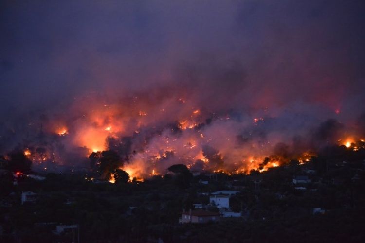 Kebakaran hutan di kota Rafina, dekat Athena, Yunani, pada Senin (23/7/2018). (AFP/Angelos Tzortzinis)