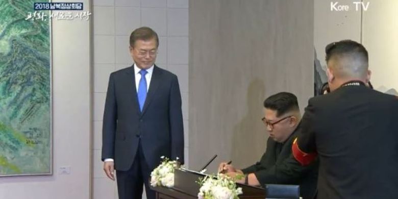 Inilah momen di mana Pemimpin Korea Utara Kim Jong Un menuliskan pesan di buku tamu disaksikan Presiden Korea Selatan Moon Jae In dalam Konferensi Tingkat Tinggi Antar-Korea di Panmunjom, Jumat (27/4/2018).
