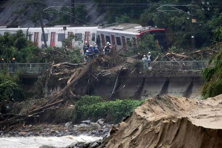 Petugas penyelamat bekerja untuk membersihkan puing di rel kereta kota Karatsu, Prefektur Saga, yang anjlok akibat tanah longsor Sabtu (7/7/2018).