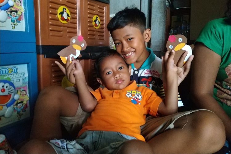 Angga, bocah pemulung asal Depok saat memangku adiknya di rumahnya daerah Kecamatan Pancoran Mas, Depok pada Selasa (20/8/2019). 