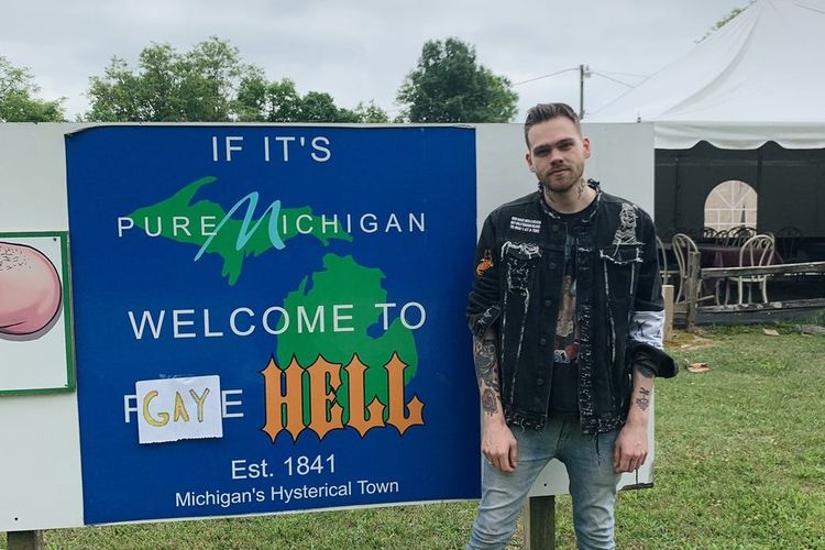 Elijah Daniel (24) berfoto di samping papan selamat datang di kota yang dibeli dan diubah namanya menjadi Gay Hell.